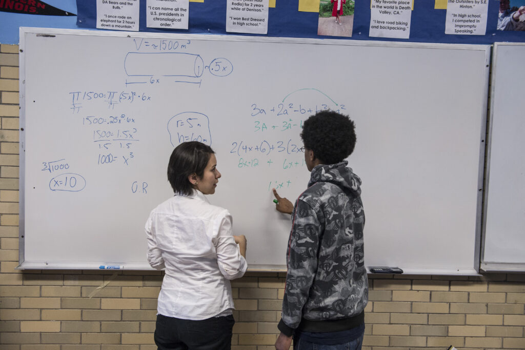 Two people stand in front of a whiteboard