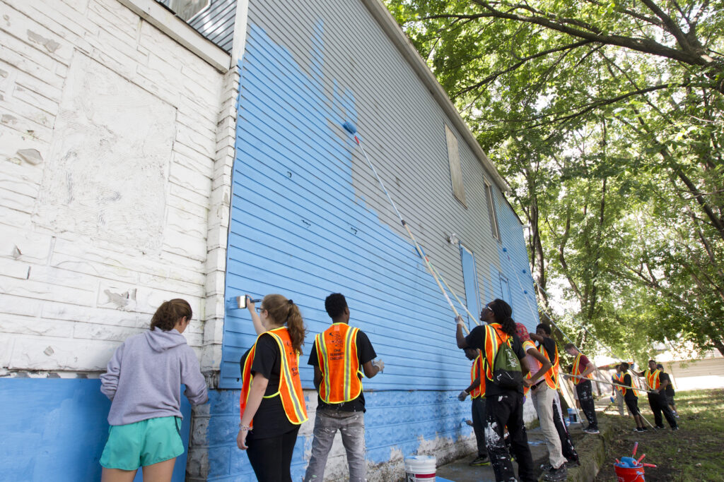 Community workers paint an old building