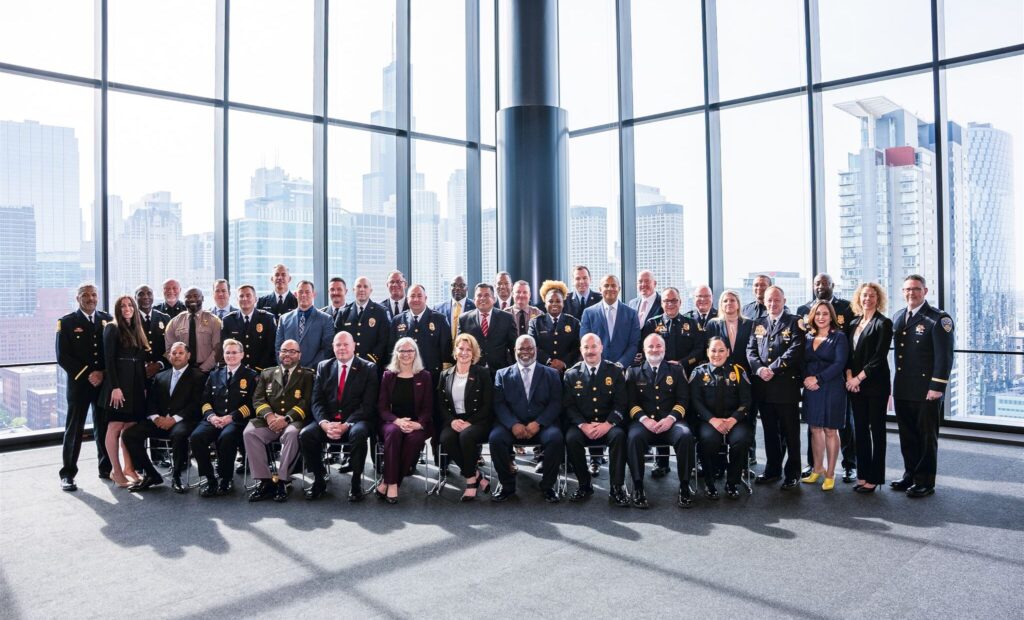 Entire cohort photo in front of large windows with Chicago skyline in the background