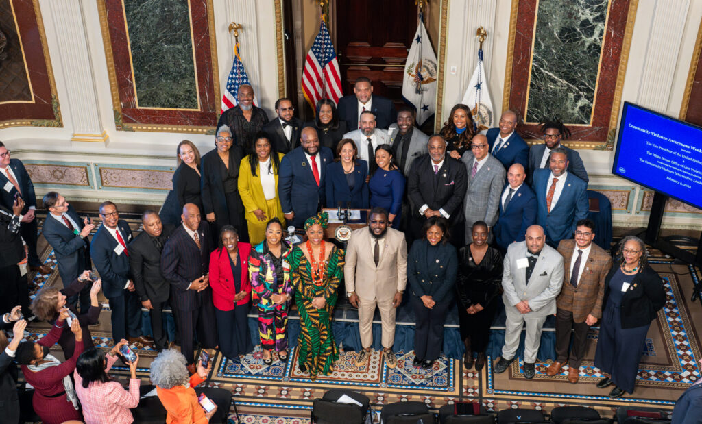 Cohort photo in the White House with Vice President Kamala Harris in the center at a podium