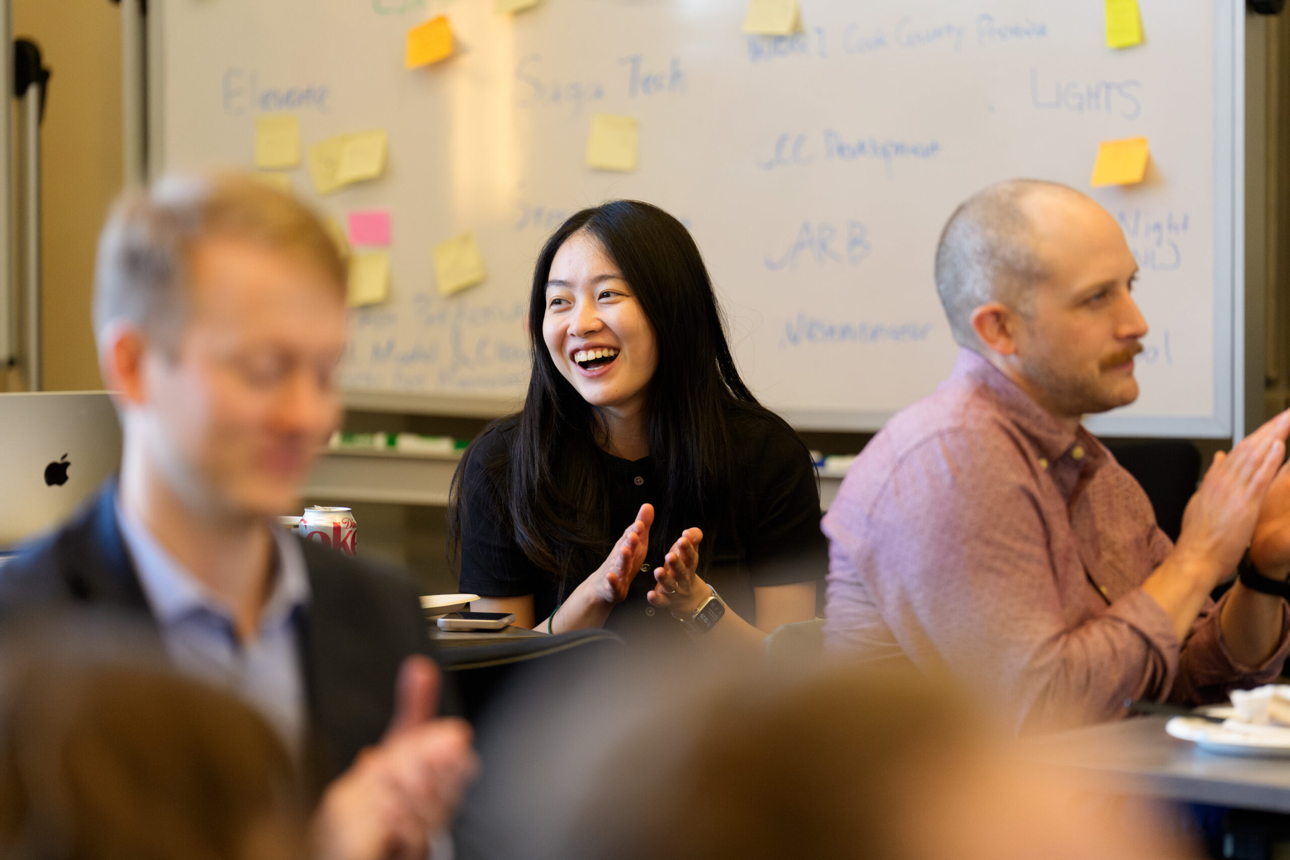 Woman smiling and clapping at a staff event